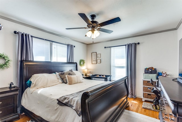 bedroom with light wood-style floors, crown molding, and a ceiling fan