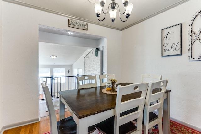 dining space featuring ornamental molding, wood finished floors, and a notable chandelier