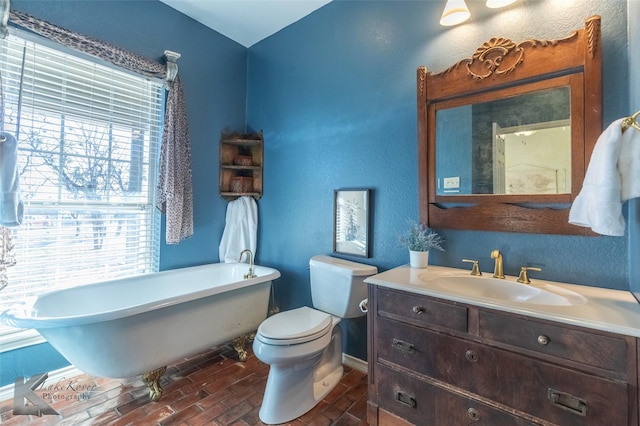 bathroom with toilet, a soaking tub, vanity, and baseboards