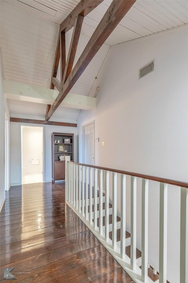 hallway featuring vaulted ceiling with beams, dark wood-style floors, and visible vents