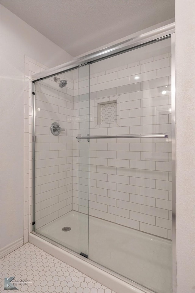 bathroom with a shower stall and tile patterned floors