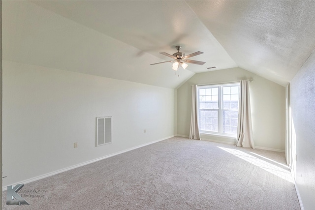 bonus room featuring carpet, visible vents, vaulted ceiling, and a textured ceiling