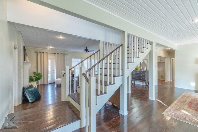 staircase featuring a fireplace, baseboards, and wood finished floors