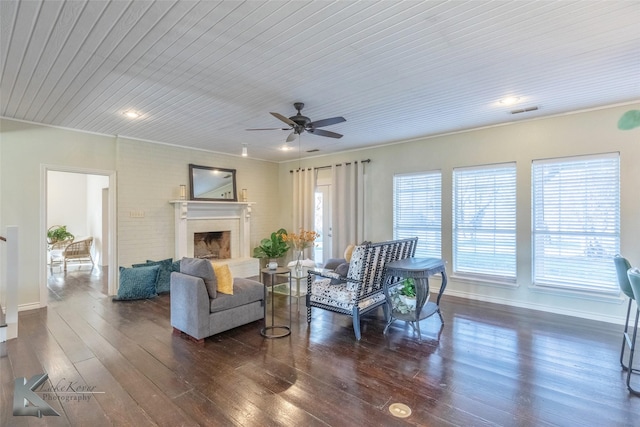 living room featuring visible vents, baseboards, a fireplace with raised hearth, and dark wood-style flooring