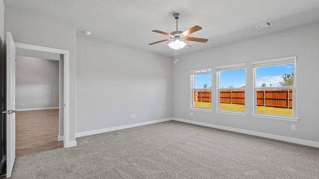 carpeted empty room with baseboards, visible vents, and ceiling fan