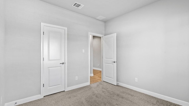 unfurnished bedroom featuring light colored carpet, visible vents, and baseboards