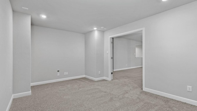 spare room with recessed lighting, light colored carpet, and baseboards