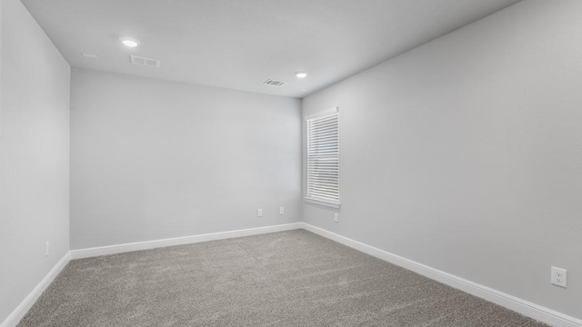 spare room with carpet floors, recessed lighting, visible vents, and baseboards