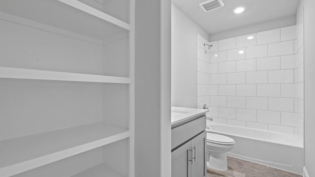 bathroom with bathtub / shower combination, visible vents, toilet, vanity, and wood finished floors