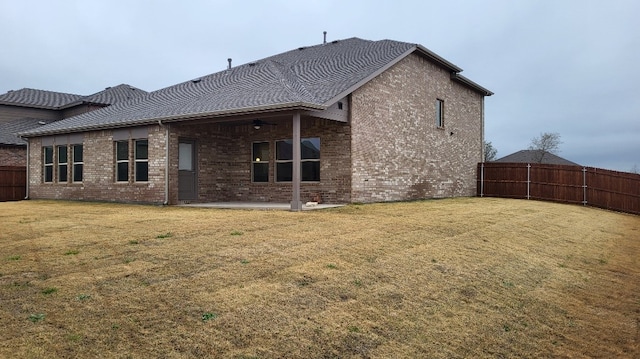 rear view of property with brick siding, a patio, a shingled roof, a lawn, and a fenced backyard