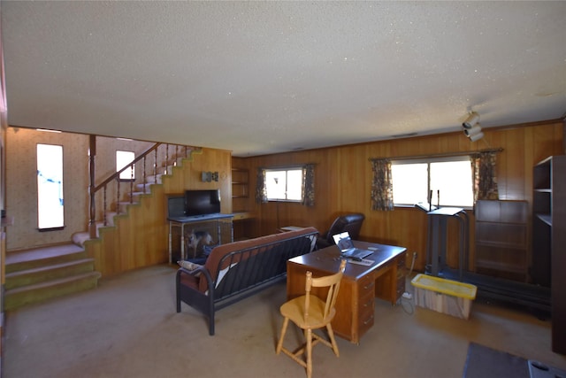 carpeted living area featuring wooden walls, a textured ceiling, and stairs