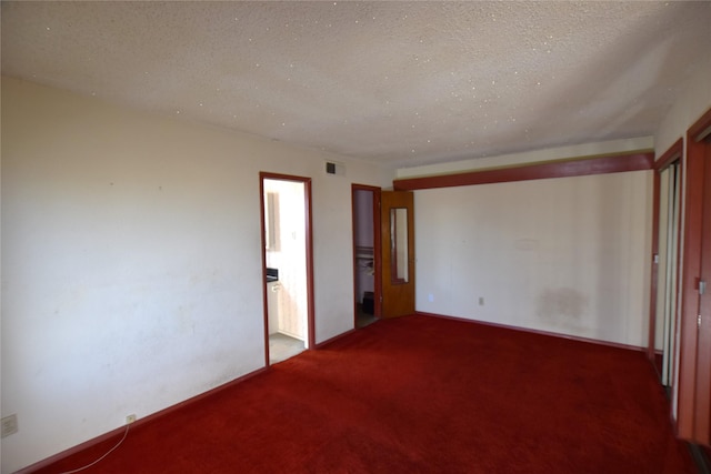 unfurnished bedroom featuring a textured ceiling, visible vents, and carpet flooring