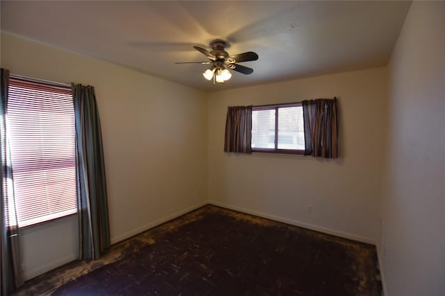 unfurnished room featuring a ceiling fan and baseboards