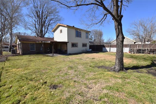 rear view of property with a yard, brick siding, and fence