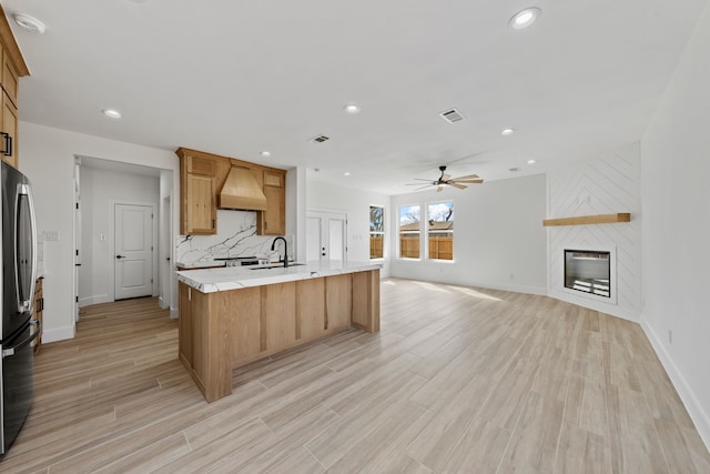 kitchen featuring a fireplace, light countertops, visible vents, open floor plan, and a sink