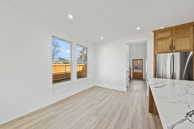 kitchen featuring baseboards, recessed lighting, freestanding refrigerator, and light wood-style floors