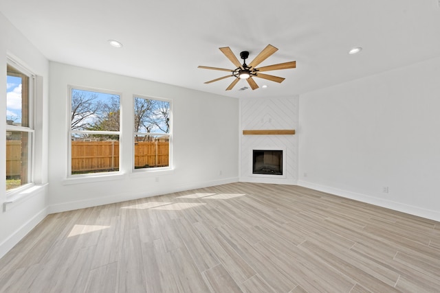 unfurnished living room featuring light wood finished floors, a fireplace, and a healthy amount of sunlight