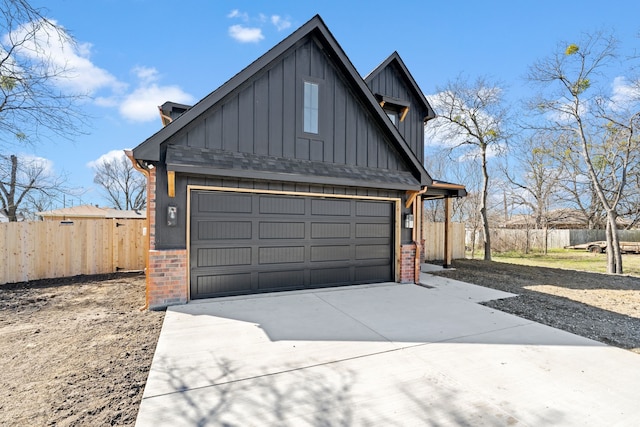 garage featuring concrete driveway and fence