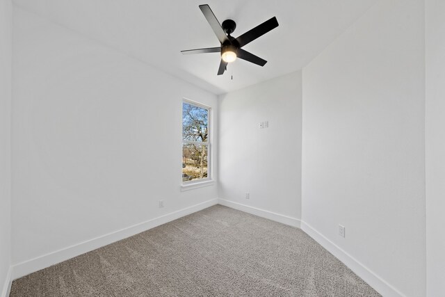 carpeted spare room featuring a ceiling fan and baseboards