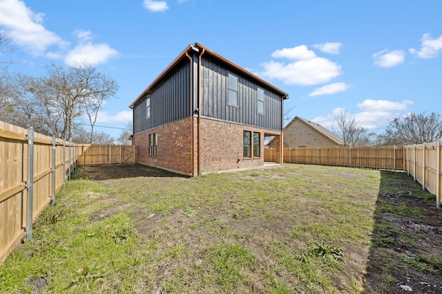 rear view of property featuring a yard, a fenced backyard, and brick siding