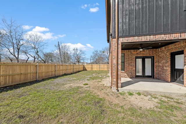 view of yard featuring ceiling fan, french doors, a patio area, and a fenced backyard