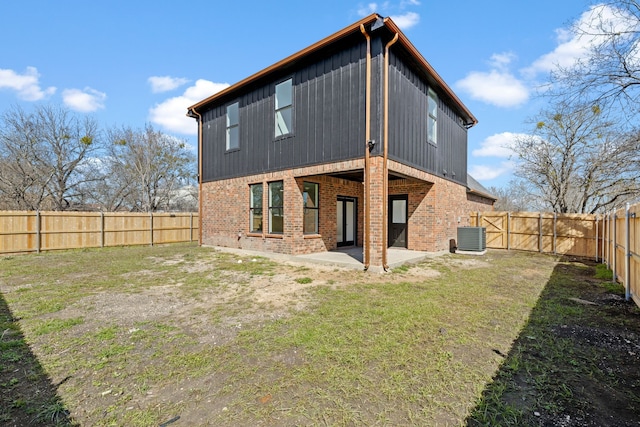 back of house featuring a fenced backyard, cooling unit, brick siding, a yard, and a patio area