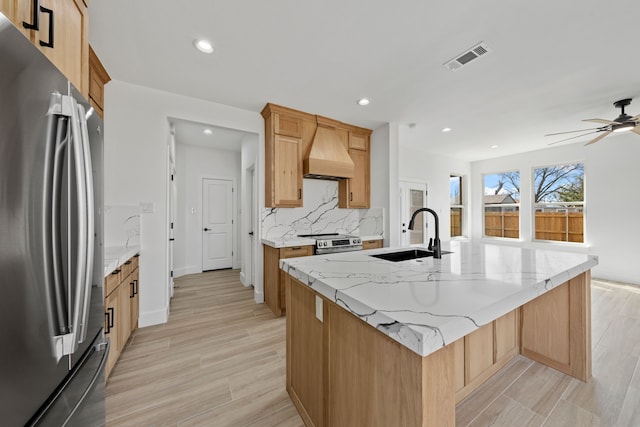 kitchen featuring visible vents, appliances with stainless steel finishes, a kitchen island with sink, custom exhaust hood, and a sink