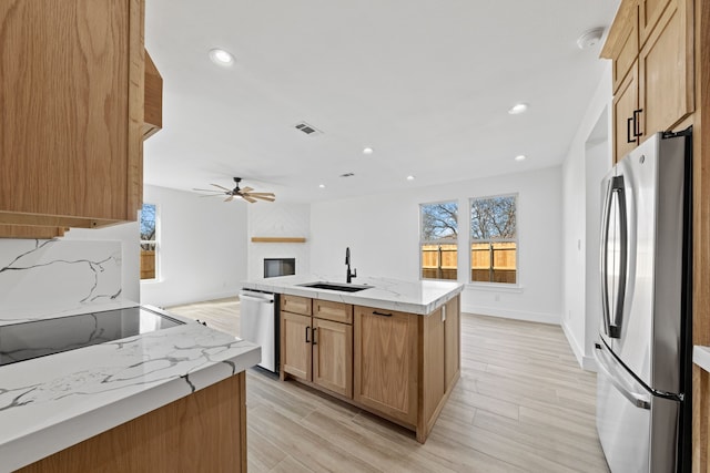 kitchen featuring visible vents, appliances with stainless steel finishes, open floor plan, a kitchen island with sink, and a sink