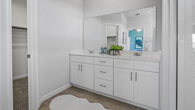 full bath featuring a sink, visible vents, baseboards, double vanity, and a walk in closet