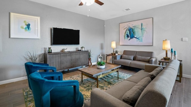 living room featuring a ceiling fan, wood tiled floor, visible vents, and baseboards