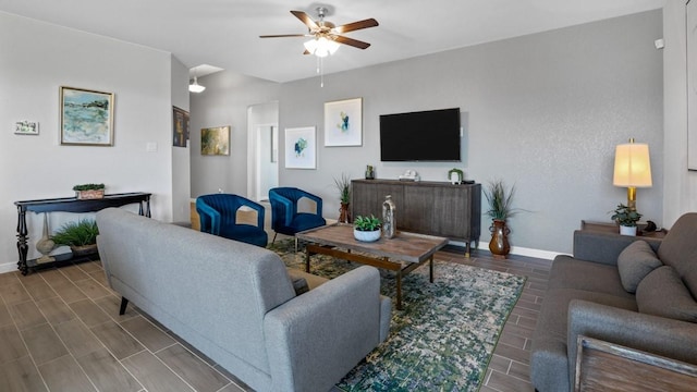 living area featuring a ceiling fan, baseboards, and wood finished floors