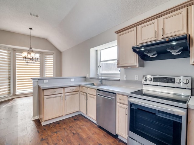 kitchen featuring appliances with stainless steel finishes, light countertops, light brown cabinetry, under cabinet range hood, and a sink