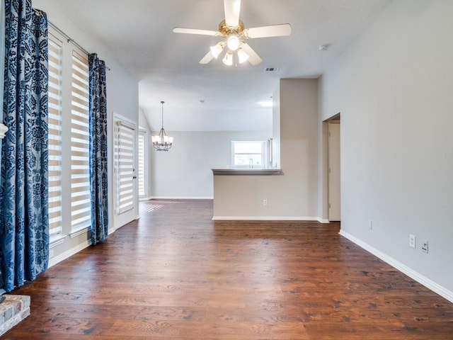 unfurnished room with ceiling fan with notable chandelier, visible vents, baseboards, vaulted ceiling, and dark wood finished floors