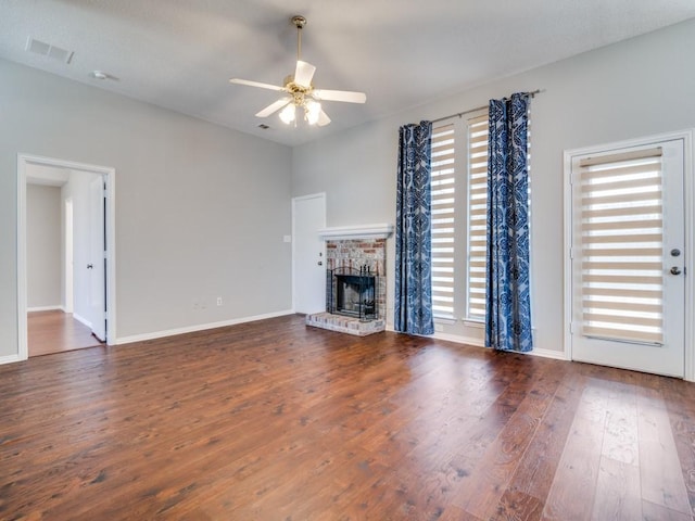 unfurnished living room featuring ceiling fan, a fireplace, visible vents, baseboards, and dark wood finished floors