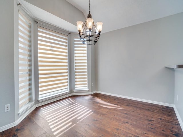 unfurnished dining area featuring lofted ceiling, dark wood-style floors, baseboards, and a notable chandelier