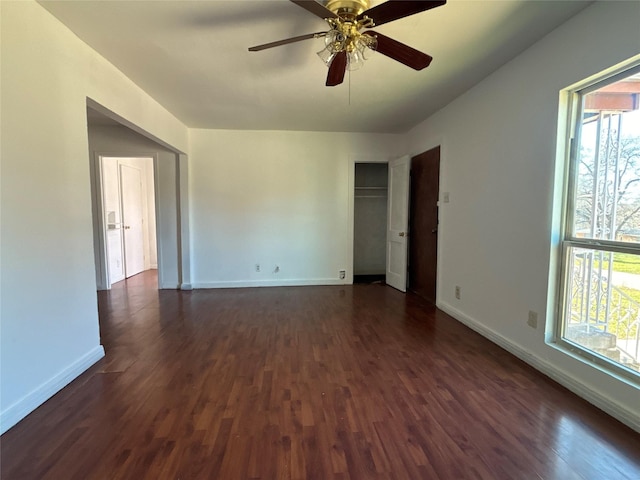 unfurnished room with baseboards, dark wood-style flooring, and a wealth of natural light