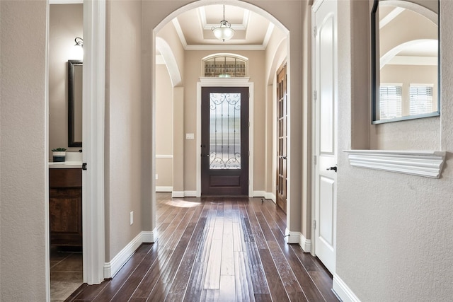 entryway featuring dark wood-style floors, baseboards, a raised ceiling, and crown molding