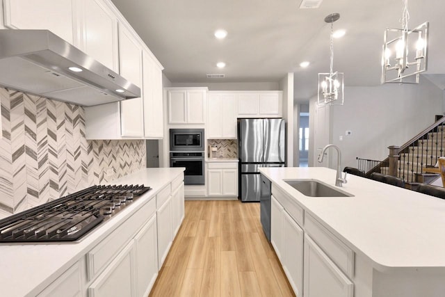 kitchen featuring a kitchen island with sink, under cabinet range hood, stainless steel appliances, a sink, and light countertops