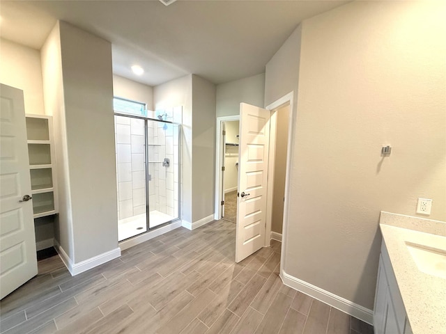 bathroom with a stall shower, wood tiled floor, a spacious closet, and baseboards