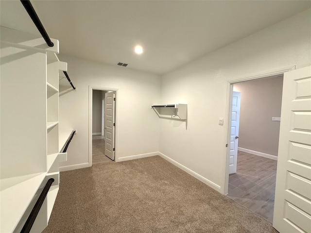 spacious closet with dark colored carpet and visible vents