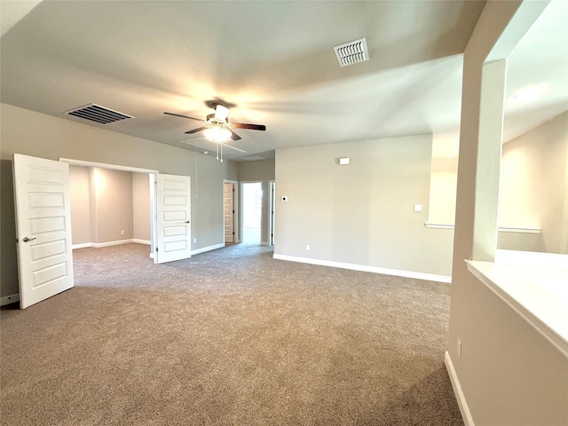 empty room with ceiling fan, carpet floors, visible vents, and baseboards