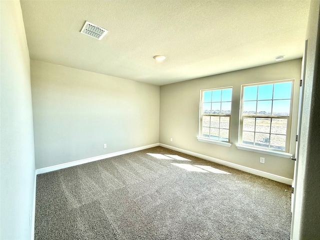 unfurnished room featuring carpet, visible vents, a textured ceiling, and baseboards