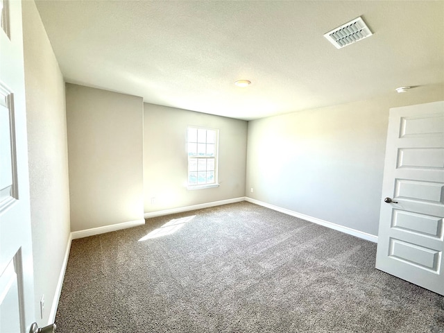 spare room featuring baseboards, visible vents, and dark carpet