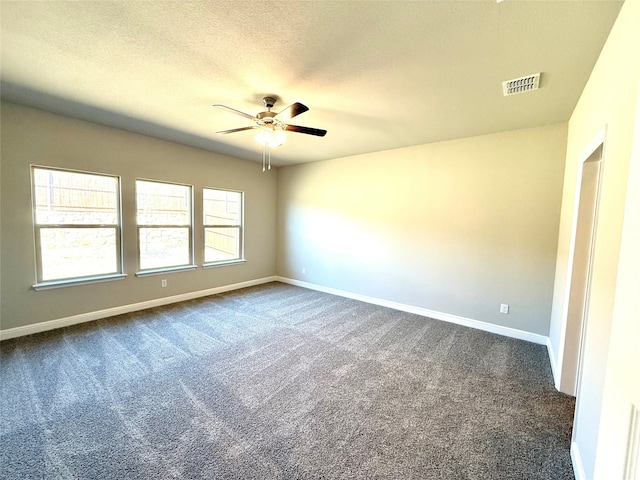 unfurnished room with baseboards, visible vents, dark colored carpet, and a textured ceiling