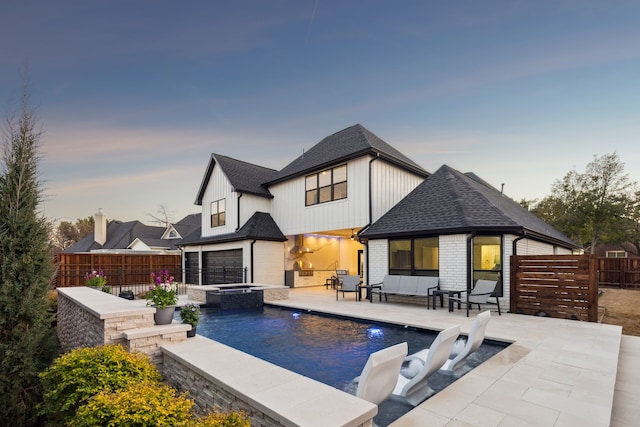 rear view of house featuring brick siding, roof with shingles, a pool with connected hot tub, a patio area, and a fenced backyard