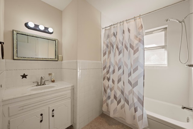 bathroom featuring a wainscoted wall, tile patterned flooring, shower / bath combo with shower curtain, vanity, and tile walls