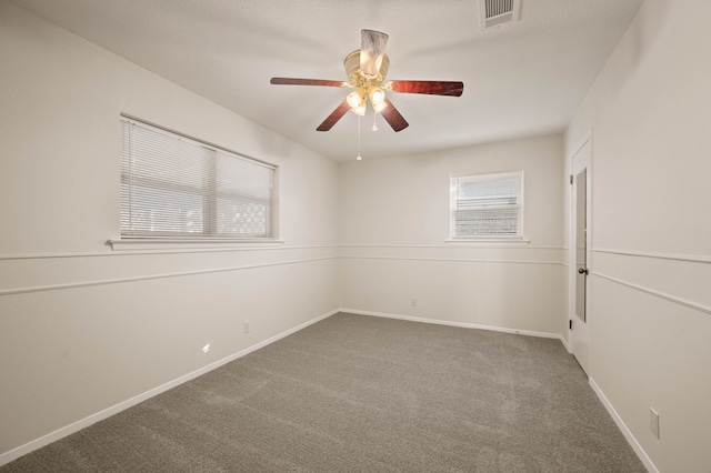 empty room featuring carpet, visible vents, a ceiling fan, and baseboards