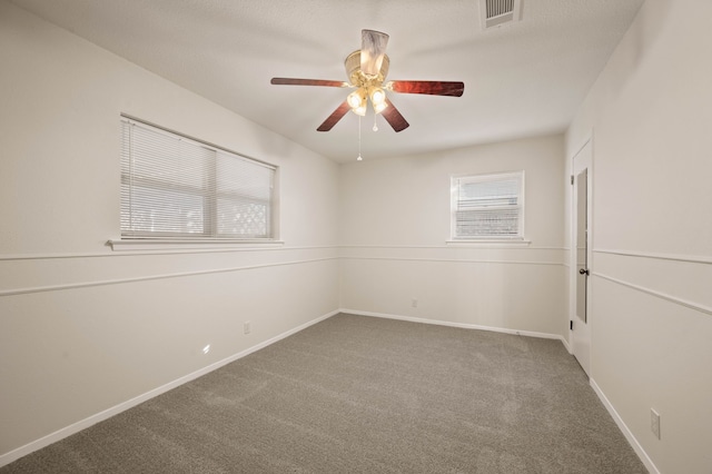 carpeted empty room with baseboards, visible vents, and ceiling fan