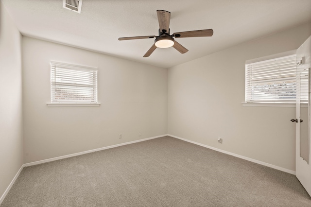 carpeted empty room featuring visible vents, ceiling fan, a wealth of natural light, and baseboards