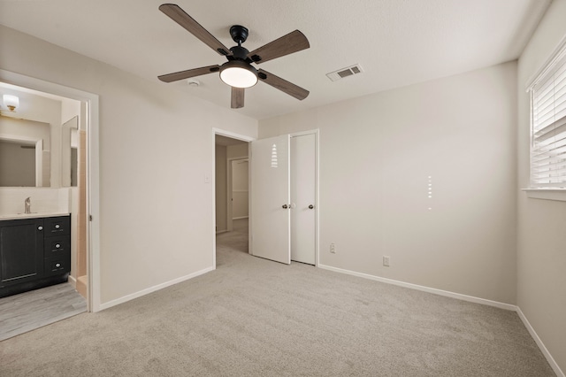 unfurnished bedroom with visible vents, a sink, light carpet, and baseboards